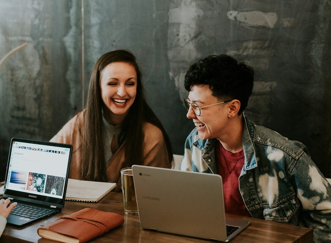 three people sitting in front of table laughing together
